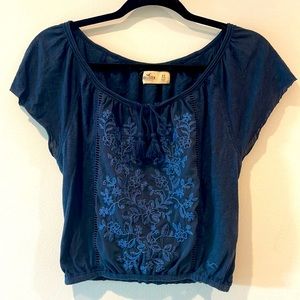 Navy flutter sleeve top with embroidered front and tassel tie at neckline